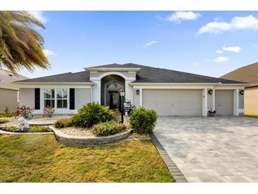 Two-story house with a three car garage and landscaping at 3545 Lia Ln, The Villages, FL 32163