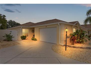 Well-maintained villa with a landscaped front yard, driveway, and garage at 419 Cambio Ct, The Villages, FL 32159