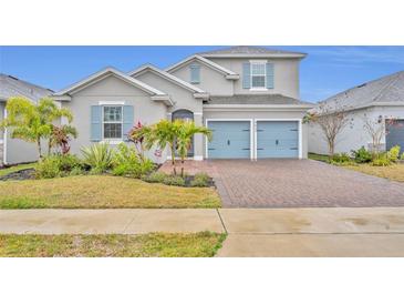 Two-story house with gray siding, blue doors, and a brick driveway at 4637 Cragmere Loop, Clermont, FL 34711