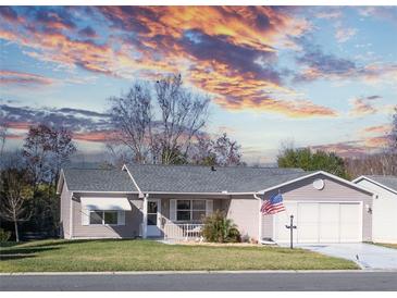 Charming single-story home featuring an attached garage, manicured lawn, and American flag at 502 San Marino Dr, Lady Lake, FL 32159