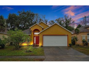 Attractive yellow house with a red door and white garage door at 7872 Niagara Falls Ct, Orlando, FL 32825