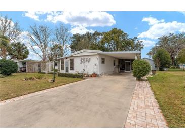 Single-wide manufactured home with carport and landscaped yard at 807 Maple Ln, The Villages, FL 32159