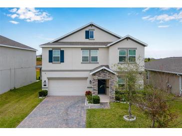 Two-story house with a gray exterior, stone accents, and a paved driveway at 848 Carmillion Ct, Groveland, FL 34736