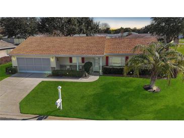 Single-story home with a brown roof, attached garage, and landscaped lawn at 13709 Se 89Th Ave, Summerfield, FL 34491