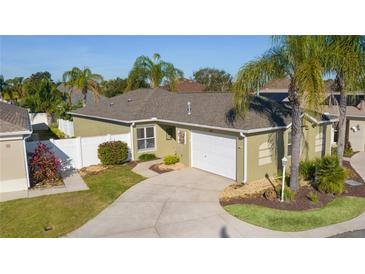 Single-story home with a green exterior, white garage door, and landscaped yard at 1418 Mccoll Ct, The Villages, FL 32162