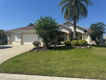 Charming single-story home featuring a well-manicured lawn, attached garage, and inviting landscaping at 1515 Gadsden Pl, The Villages, FL 32162
