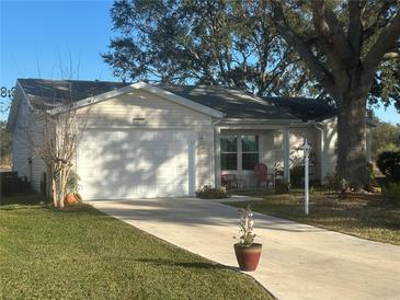Single-story home with a white exterior, a two-car garage, and a well-maintained lawn at 24825 Pine Hl, Leesburg, FL 34748