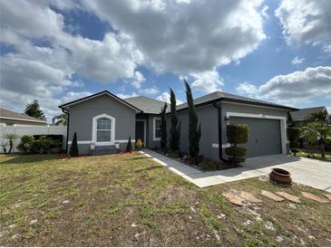 Charming single-story home boasts a manicured lawn and attached two car garage and welcoming walkway at 5756 Lakeside Landings Blvd, Winter Haven, FL 33881