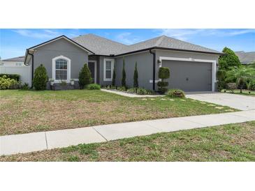 One-story home with gray siding, landscaping, and a two-car garage at 5756 Lakeside Landings Blvd, Winter Haven, FL 33881