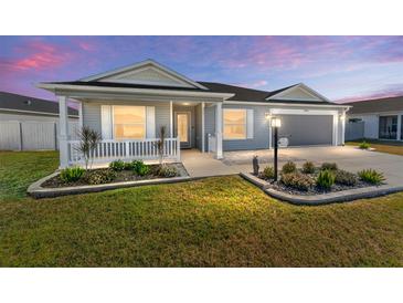 Gray house with a white porch and landscaping at 6764 Mary Loop, The Villages, FL 34762