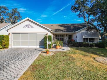 Single-story home with a paved driveway, attached garage, and well-maintained landscaping at 901 Pasadena Way, Lady Lake, FL 32159