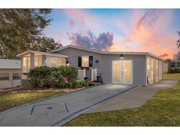 Updated manufactured home with a gray exterior, new landscaping, and a paved driveway at 1404 Torrey Pines Dr, The Villages, FL 32159
