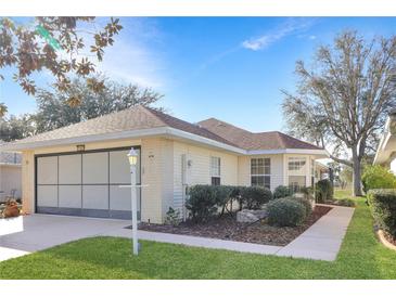 Brick ranch home with screened garage, landscaped yard, and walkway at 21837 Royal St Georges Ln, Leesburg, FL 34748
