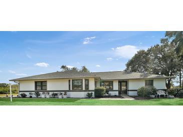 Single-story home with gray roof, white walls, and landscaped lawn at 26500 Wimbledon St, Leesburg, FL 34748