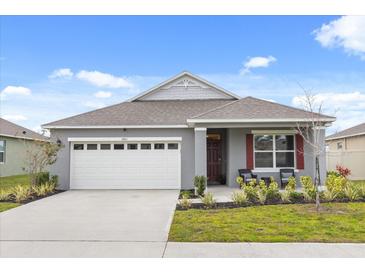 Gray house with white garage door, red shutters, and landscaping at 4861 Panga Ave, Mount Dora, FL 32757
