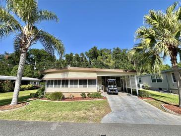 Charming single-story home with lush landscaping and a covered carport for convenient parking at 114 Chestnut St, Leesburg, FL 34748