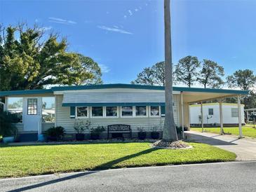 Charming home with well-maintained lawn, mature trees, and convenient covered carport at 136 Dogwood Trl, Leesburg, FL 34748