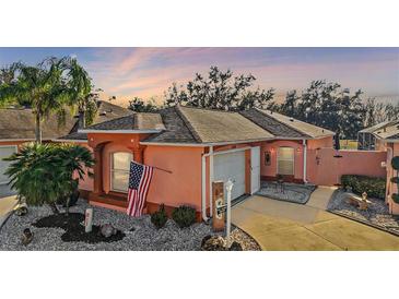 Attractive single-story home with a peach-colored exterior, American flag, and well-maintained landscaping at 1504 Aalto Pl, The Villages, FL 32159