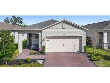 One-story house with gray siding, brick driveway, and landscaping at 17442 Blazing Star Cir, Clermont, FL 34714