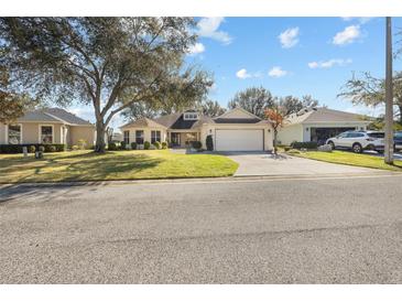 Single-story home with a two-car garage and well-maintained lawn at 26709 Augusta Springs Cir, Leesburg, FL 34748