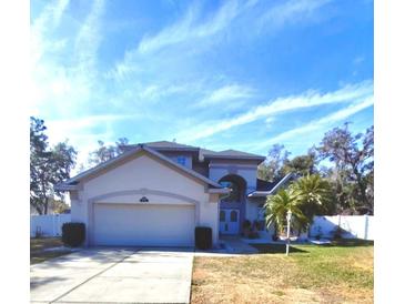 Two-story home features an attached garage, a well-kept lawn and a blue sky background at 33025 Jodee Ct, Leesburg, FL 34788