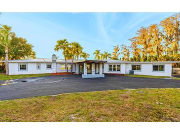 Updated home with gray exterior, metal roof, and large driveway at 5526 Parkdale Dr, Orlando, FL 32839