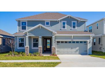 Two-story house with gray siding, stone accents, and a two-car garage at 1304 Silo Dr, St Cloud, FL 34771