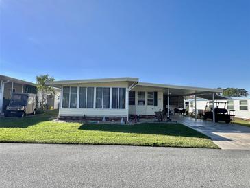 Charming manufactured home featuring a sunroom, carport, and well-maintained lawn at 188 Hibiscus Way, Leesburg, FL 34748