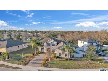 Two-story home featuring manicured landscaping and a long, patterned driveway lined with palm trees at 3463 Creek Run Ln, Eustis, FL 32736