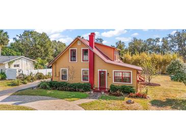 Charming yellow house with red trim, landscaped yard, and paved driveway at 7206 Earlwood Ave, Mount Dora, FL 32757