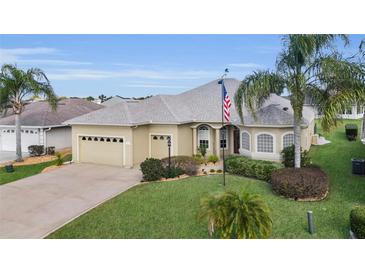 Charming single-story home featuring a well-manicured lawn, two-car garage, and beautiful landscaping at 12163 Se 176Th Loop, Summerfield, FL 34491