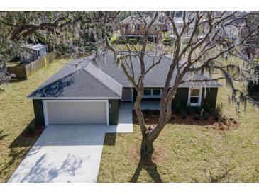 Charming home featuring a two-car garage, complemented by a well-manicured lawn and a large shade tree at 1511 Moss Ave, Leesburg, FL 34748