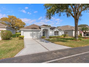 Charming single-story home with a well-manicured lawn, a two-car garage, and an inviting front entrance with an arched entryway at 3637 Hawkshead Dr, Clermont, FL 34711