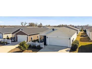 Two-story home with attached garage and white picket fence at 3818 Zentko St, The Villages, FL 32163