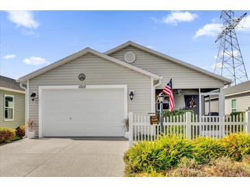 Tan one-story house with white picket fence and American flag at 6206 Dingman Way, The Villages, FL 32163