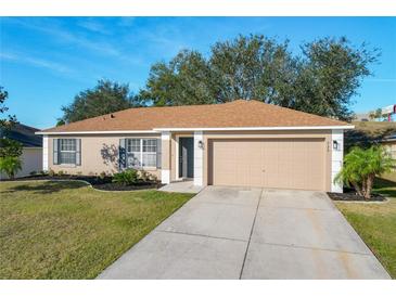 Tan one-story house with a two-car garage and landscaped lawn at 733 Cherry Laurel St, Minneola, FL 34715