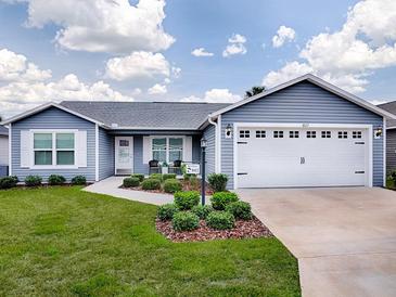 Charming single-story home featuring a well-manicured lawn, inviting entryway, and an attached two-car garage at 802 Nancy Dr, The Villages, FL 32163