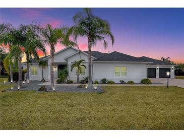 Stunning curb appeal featuring a white two-story house with palm trees and well-manicured lawn at 858 Pinckney Ln, The Villages, FL 32162