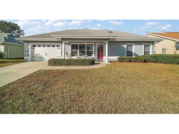 One-story home with gray exterior, white garage door, and red front door at 11579 Se 172Nd Loop, Summerfield, FL 34491