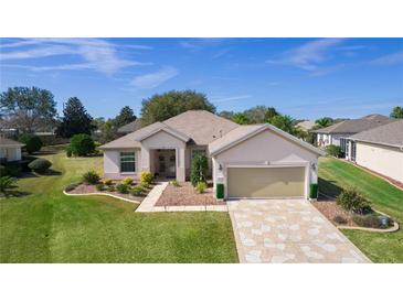 Charming single-story home with landscaped front yard and patterned driveway, offering great curb appeal at 13914 Se 96Th Cir, Summerfield, FL 34491