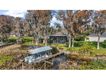 Waterfront home featuring a private boat dock and lift surrounded by lush greenery and mature trees at 1702 N County Road 452, Eustis, FL 32726