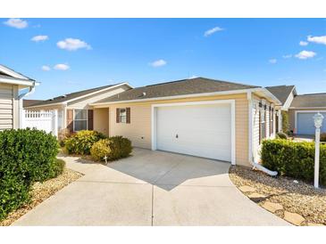 Charming home exterior featuring a one car garage, neutral paint, well-manicured landscaping, and a concrete drive at 2303 Nehaul Ter, The Villages, FL 32162