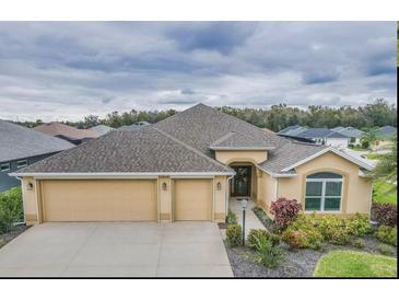 Charming single-story home with well-manicured landscaping and a three-car garage on an overcast day at 5424 Donahe Path, The Villages, FL 32163