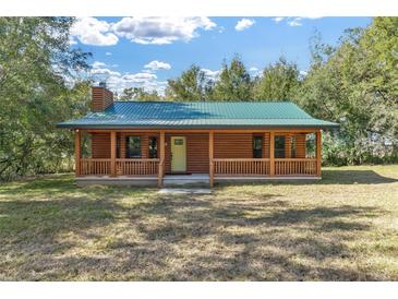 Charming log cabin with a metal roof and a welcoming covered front porch at 775 Abeble Rd, Lady Lake, FL 32159