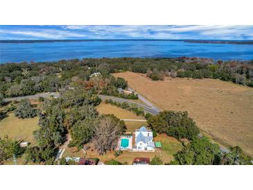 Expansive lakefront property with lush landscaping, pool, and a charming two-story farmhouse at 9210 County Road 48, Yalaha, FL 34797