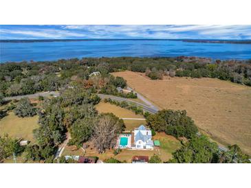 Aerial view of waterfront property with home, pool, and expansive land at 9210 County Road 48, Yalaha, FL 34797