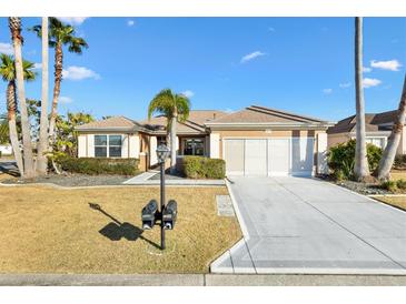 Charming single-story home featuring a well-manicured lawn, complemented by palm trees and an attached two-car garage at 12455 Se 92Nd Ter, Summerfield, FL 34491