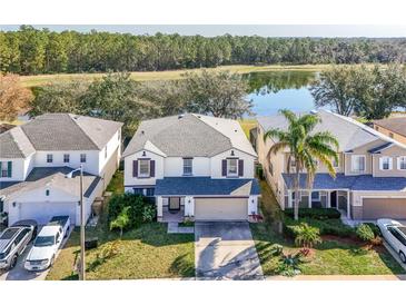 Aerial view of a two story house with a lake and trees in the background at 16825 Sunrise Vista Dr, Clermont, FL 34714