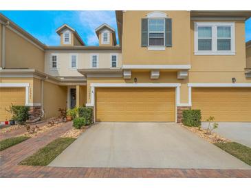 Charming townhome exterior with a brick pathway and well-maintained landscaping and a one car garage at 17523 Promenade Dr, Clermont, FL 34711