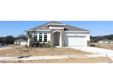 Charming single-Gathering home with stone accents, arched entryway, and a two-car garage at 2803 Supermarine Rd, Tavares, FL 32778
